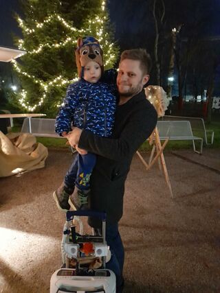 Samuel mit seinem Papa. Vorn im Bild ist das Kunstherz, das er überall mitnehmen muss. Durch einen Schlauch ist es mit seinem Herz verbunden (Foto: Unser Würmtal)