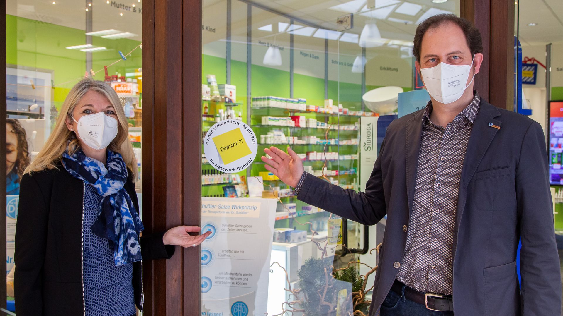 Petra Fontana (Fachstelle für Senioren) und Apotheker Raphael Felber präsentieren das Logo „Demenzfreundliche Apotheke“.