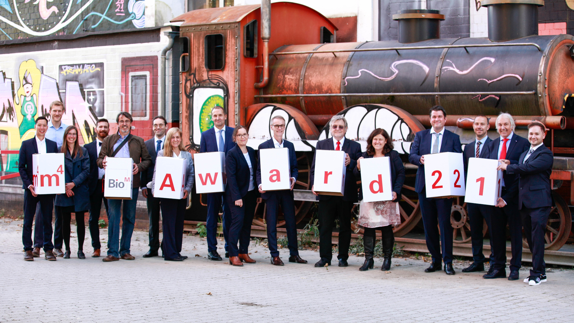 Die Gewinner-Team des m4 Awards 2021 mit Dr. Manfred Wolter (StMWi, 7. von rechts) und Prof. Horst Domdey (BioM, 6. von rechts). (Foto: BioM)